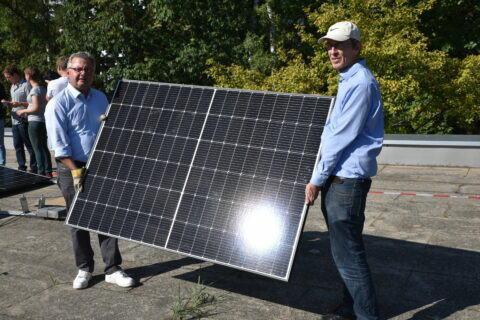 Hochhalten einer PV Anlage von 2 Personen