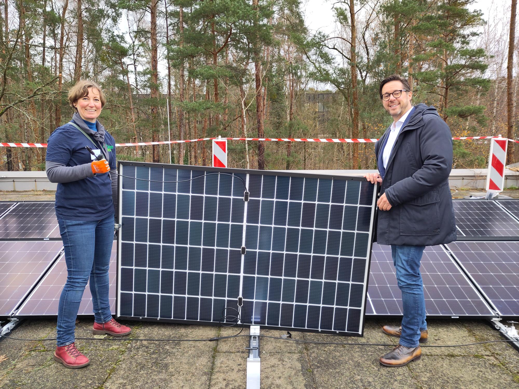 PV-Bau 3.12.2024 (Laserphysik): Während der Bauphase der Anlage. Zwei Personen tragen ein PV-Modul.