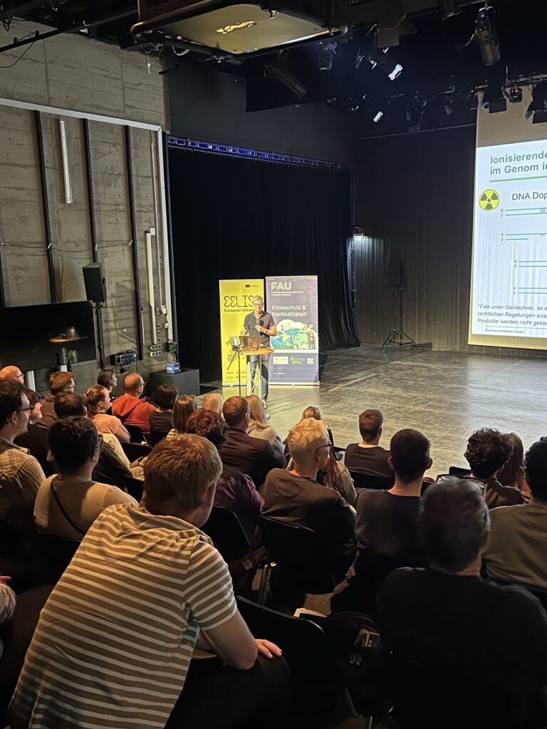 Zu sehen sind Roll-Ups von EELISA und dem Green Office, ein Publikum und eine Person auf der Bühne.