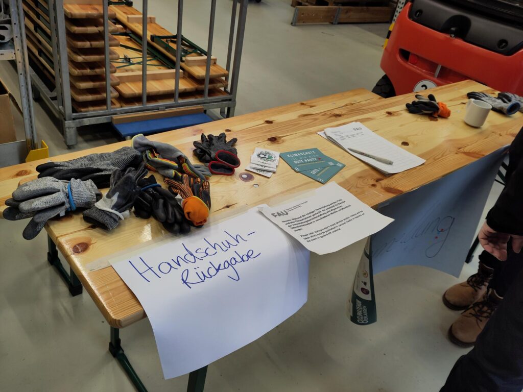 Auf dem Foto ist ein Biertisch abgebildet, auf dem Arbeitsandschuhe und verschiedene Formulare liegen.