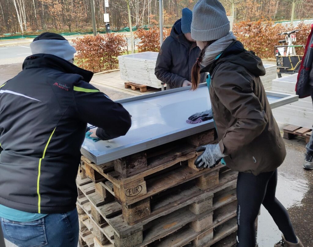 Auf dem Foto sind 3 Personen abgebildet, die gerade ein PV-Modul reinigen.