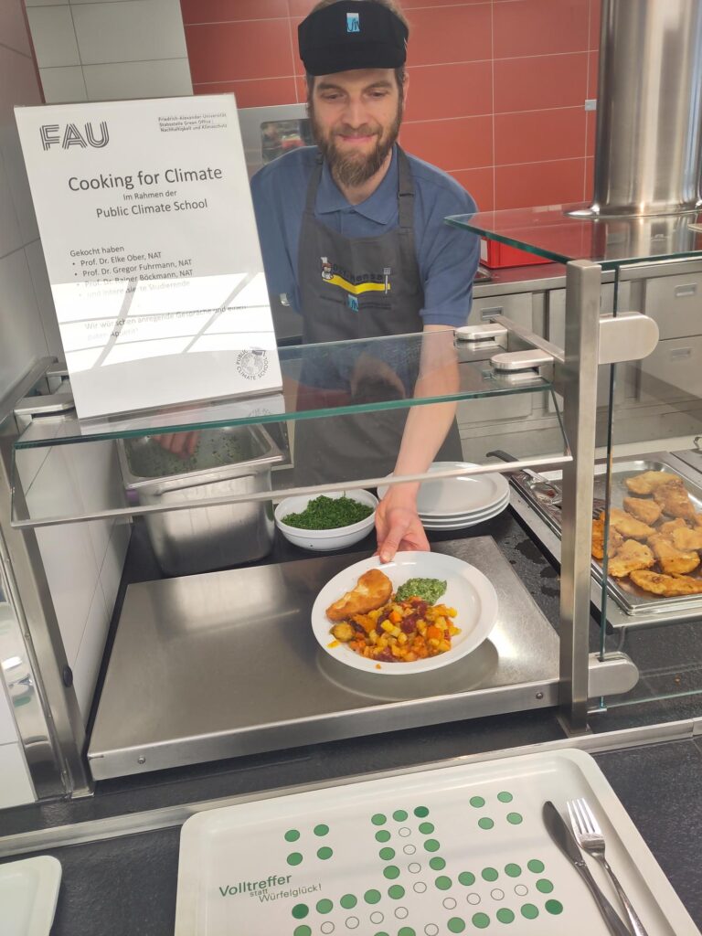 AUf dem Foto ist eine Person zu sehen, die gerade Essen an der Mensa-Theke ausgibt.