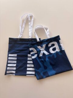 Auf dem Foto sind zwei selbst genähte Taschen zu sehen, die aus einer blauen FAU-Fahne upgecycelt wurden.